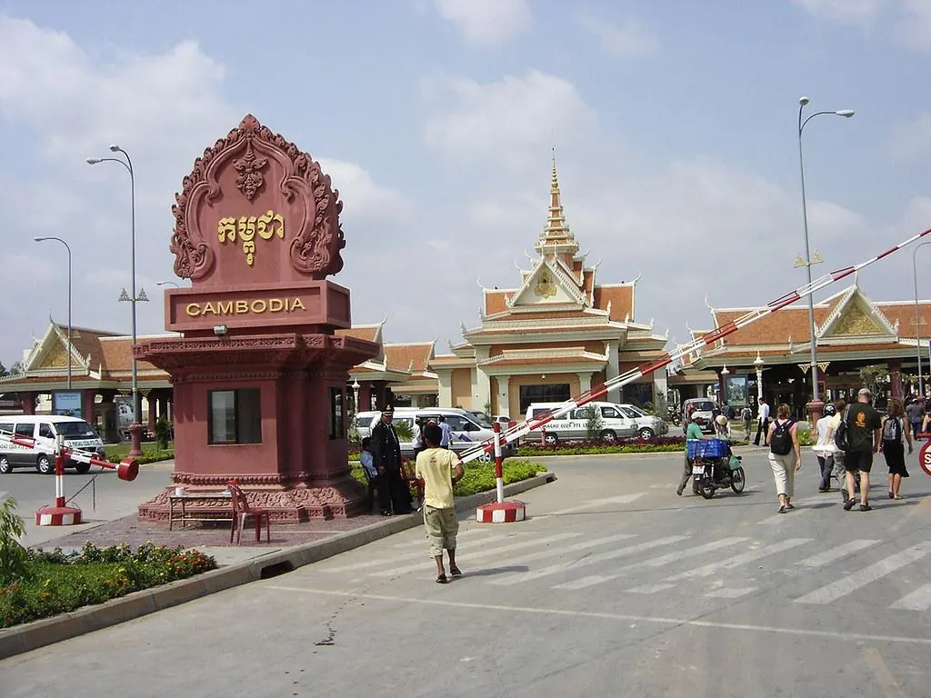 Travellers walking past the Cambodia welcome arch at Bavet